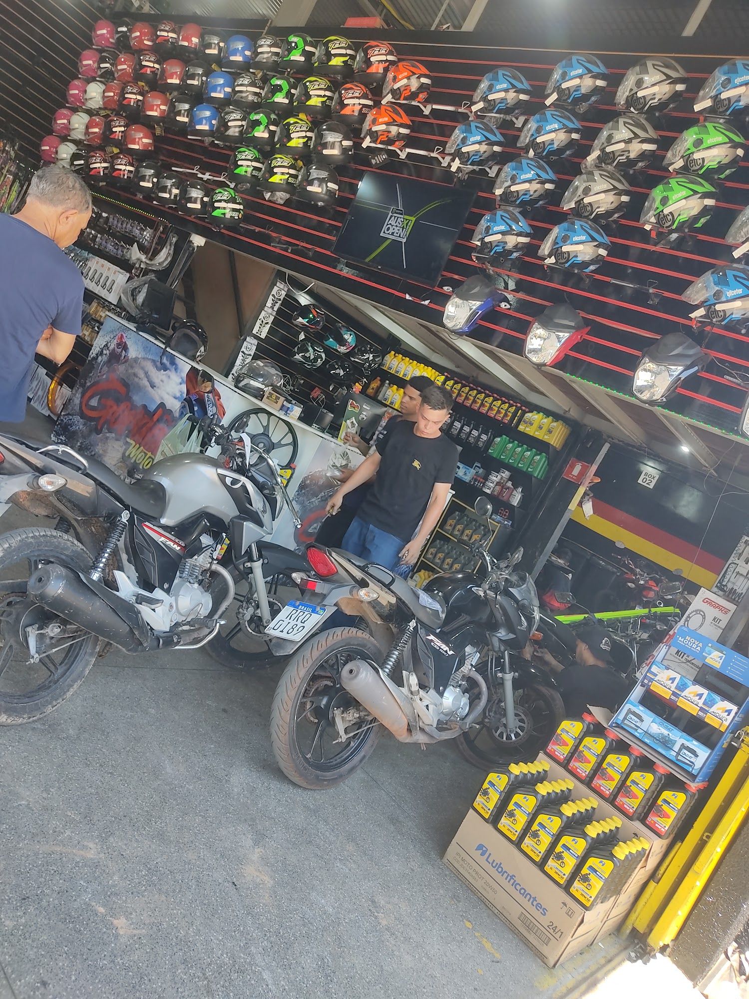 Mecânico da Gordão Motos atendendo cliente com duas motos na frente do balcão