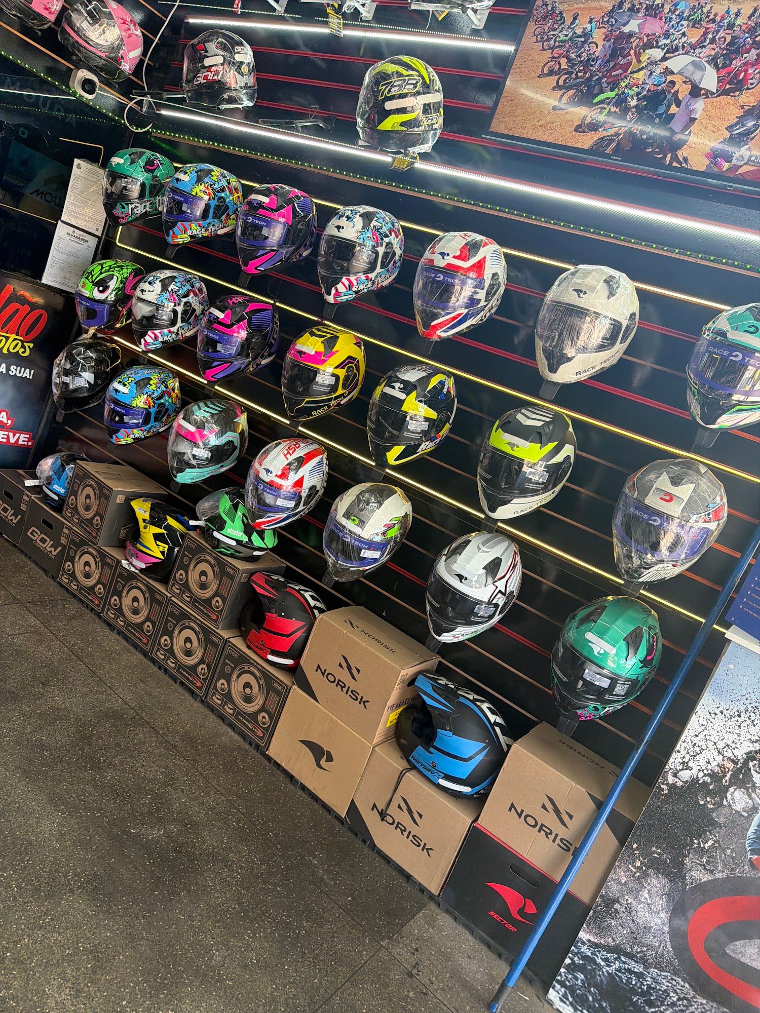 Parede de capacetes coloridos iluminados por LED e caixas de capacete no chão